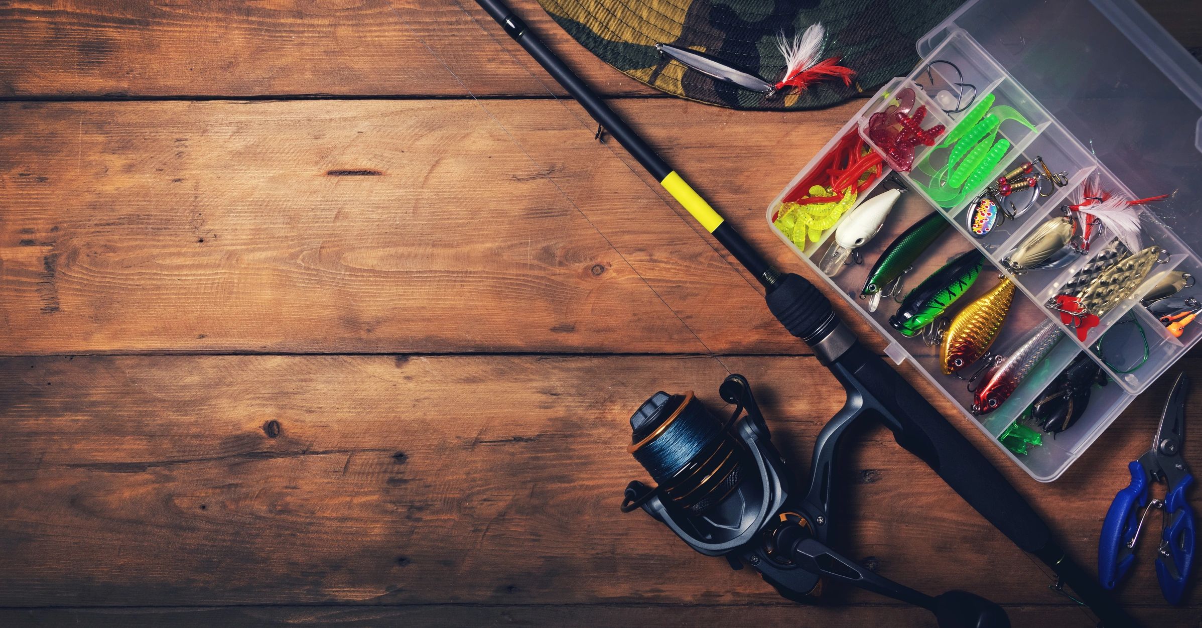 Fishing tackle and lures laid out on a wooden surface