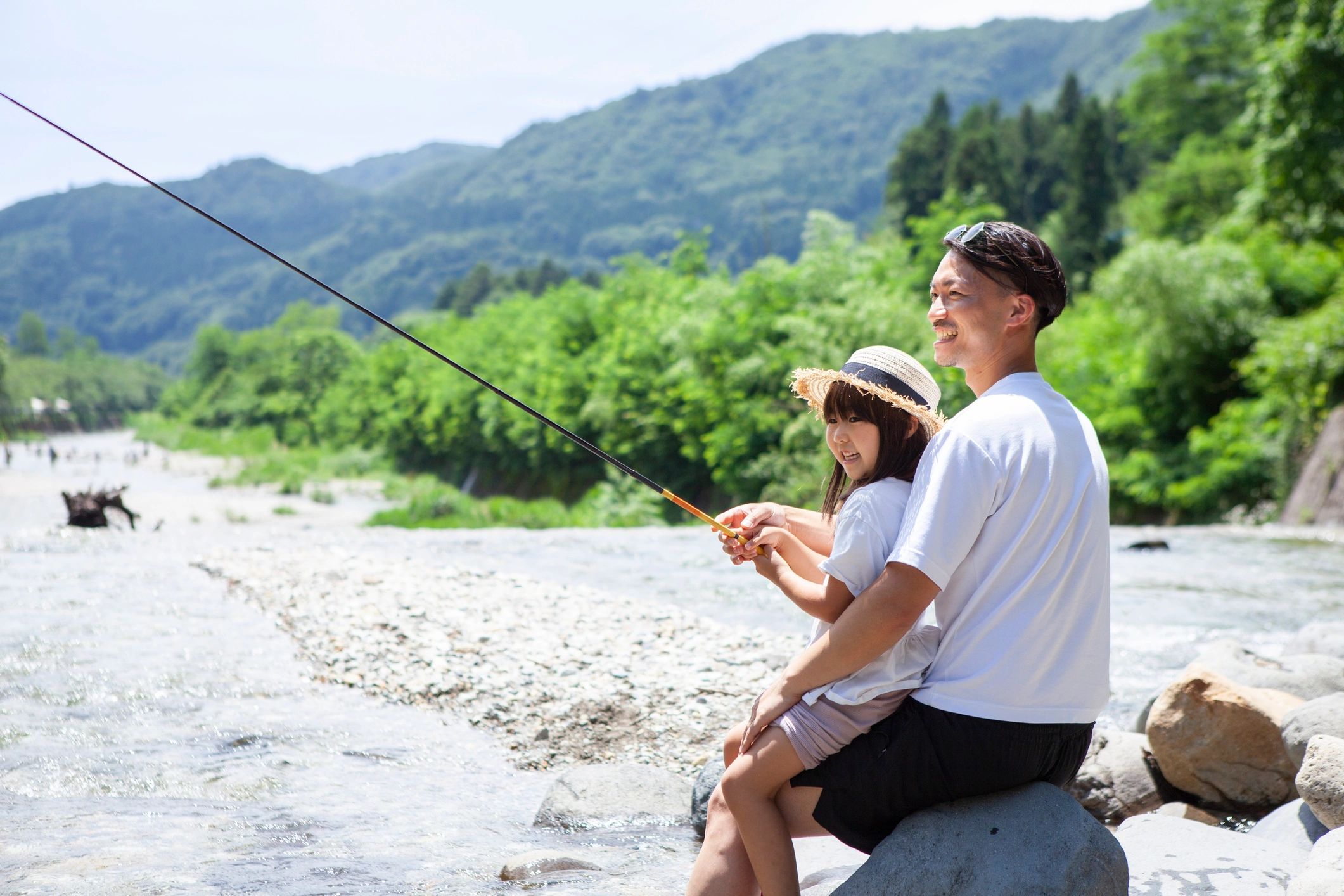 Parent and child fishing together on a riverbank