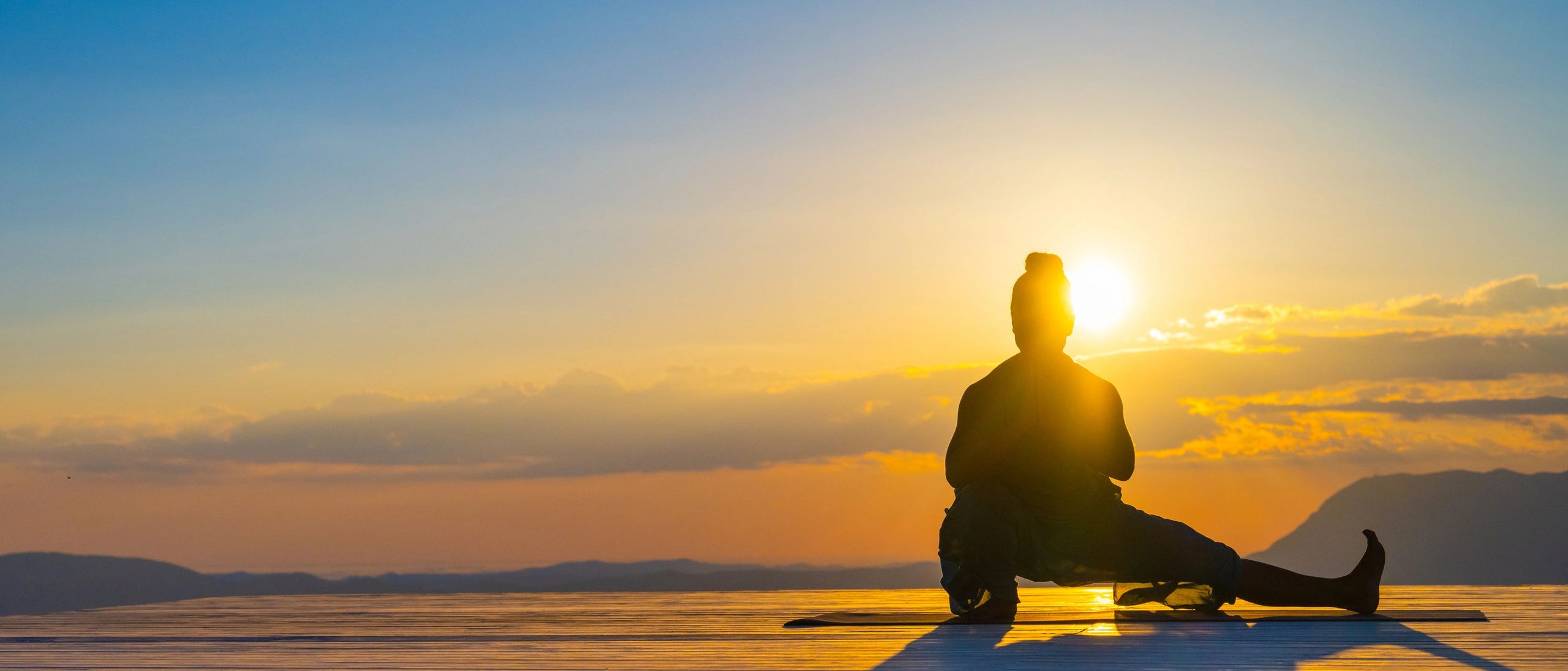 Angler casting a fishing rod at sunrise on calm water