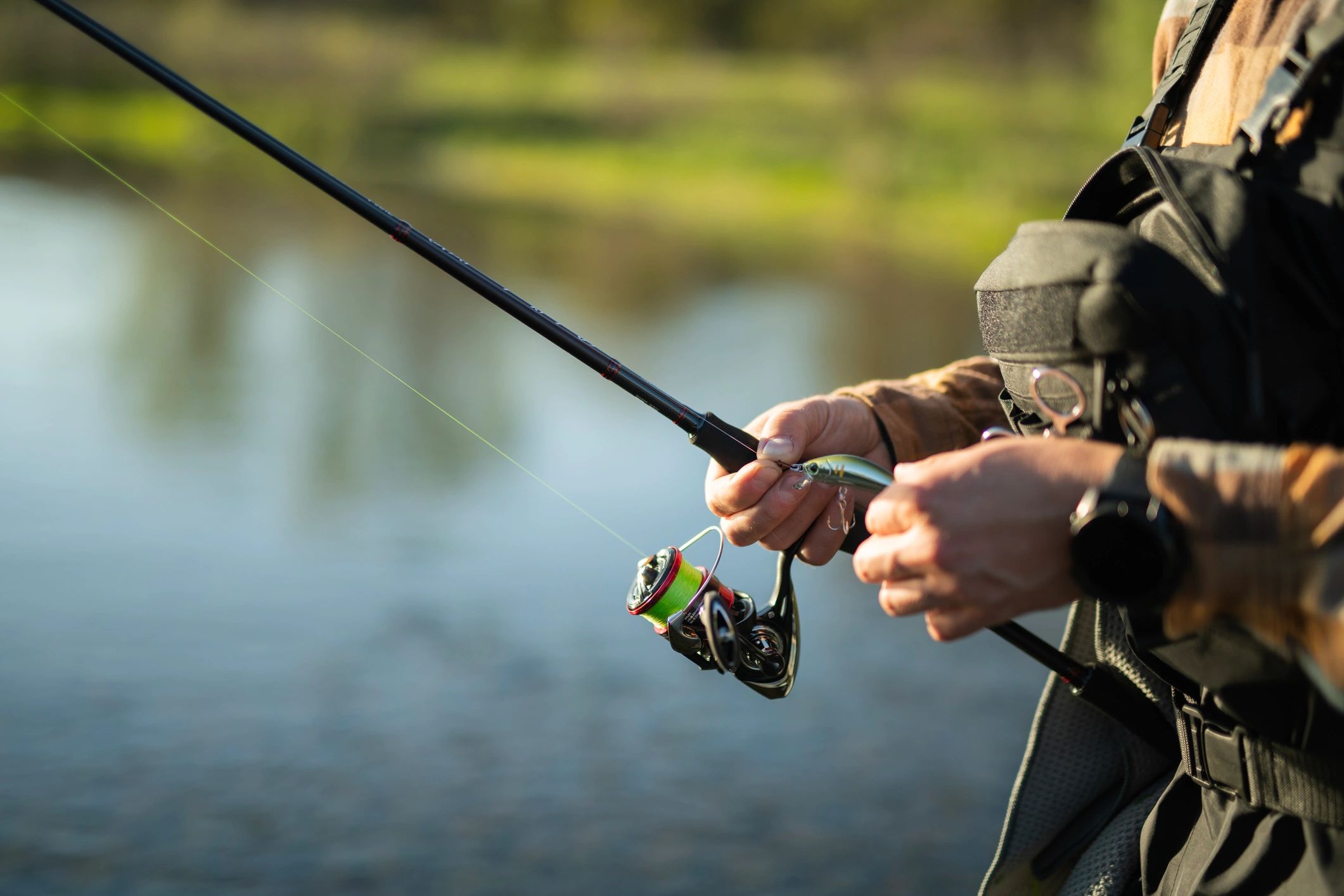 Close-up of an angler preparing bait on a rod at sunset