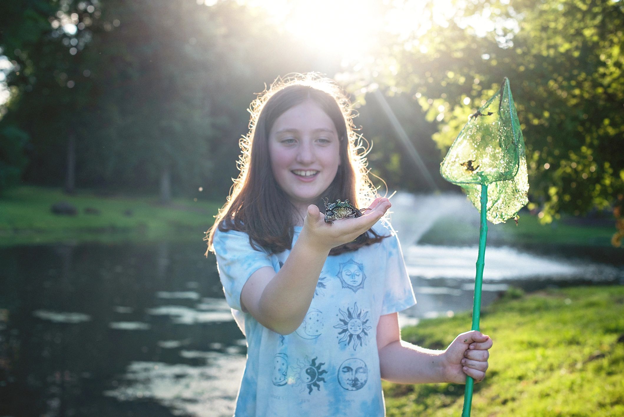 Young angler holding a small catch by a pond