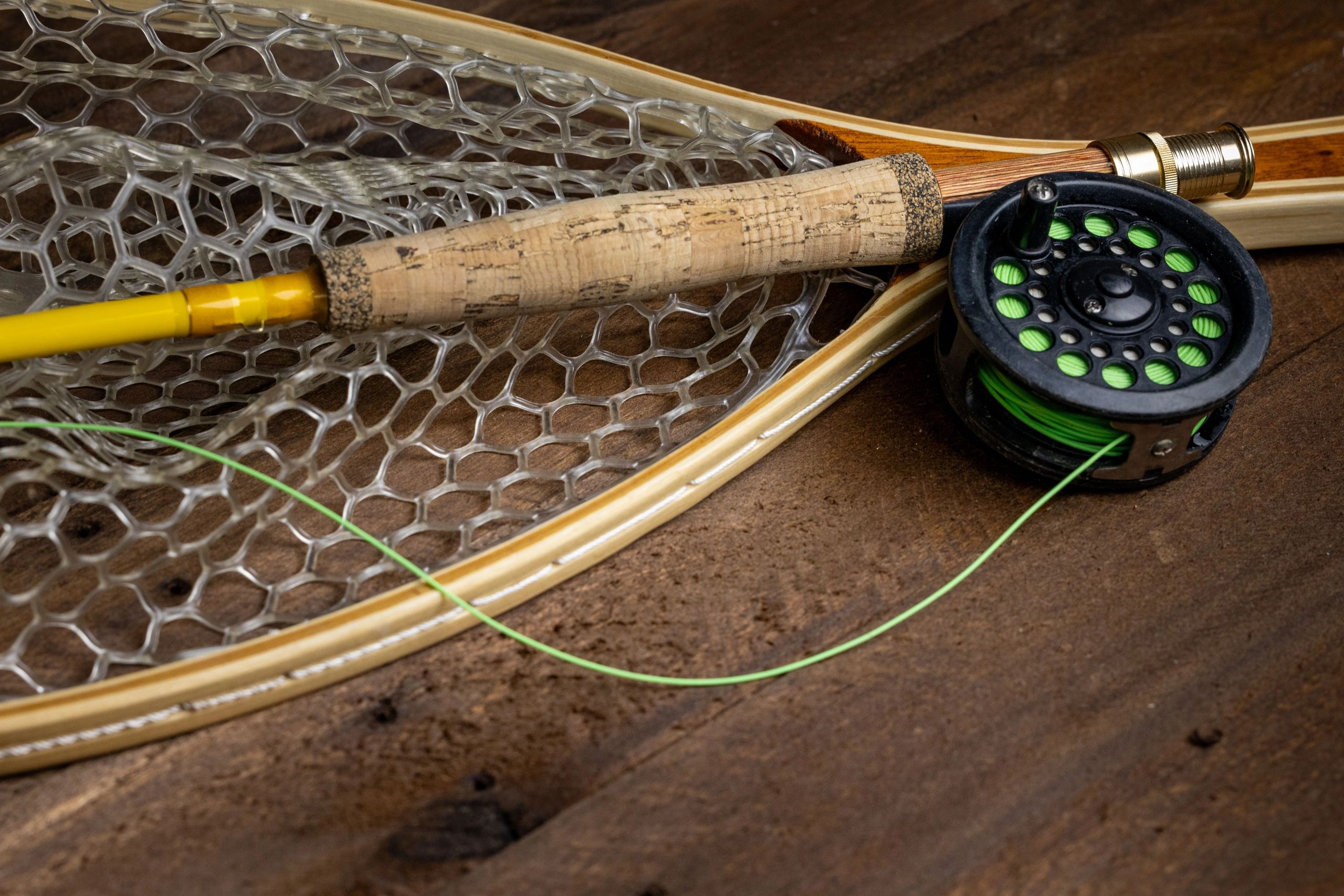 Close-up of fly fishing reel and gear on a wooden surface
