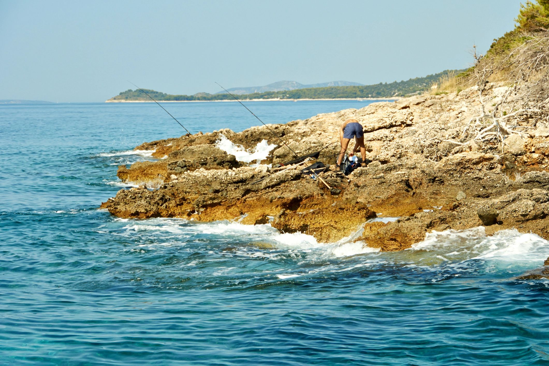 Fisherman casting from a rocky shoreline